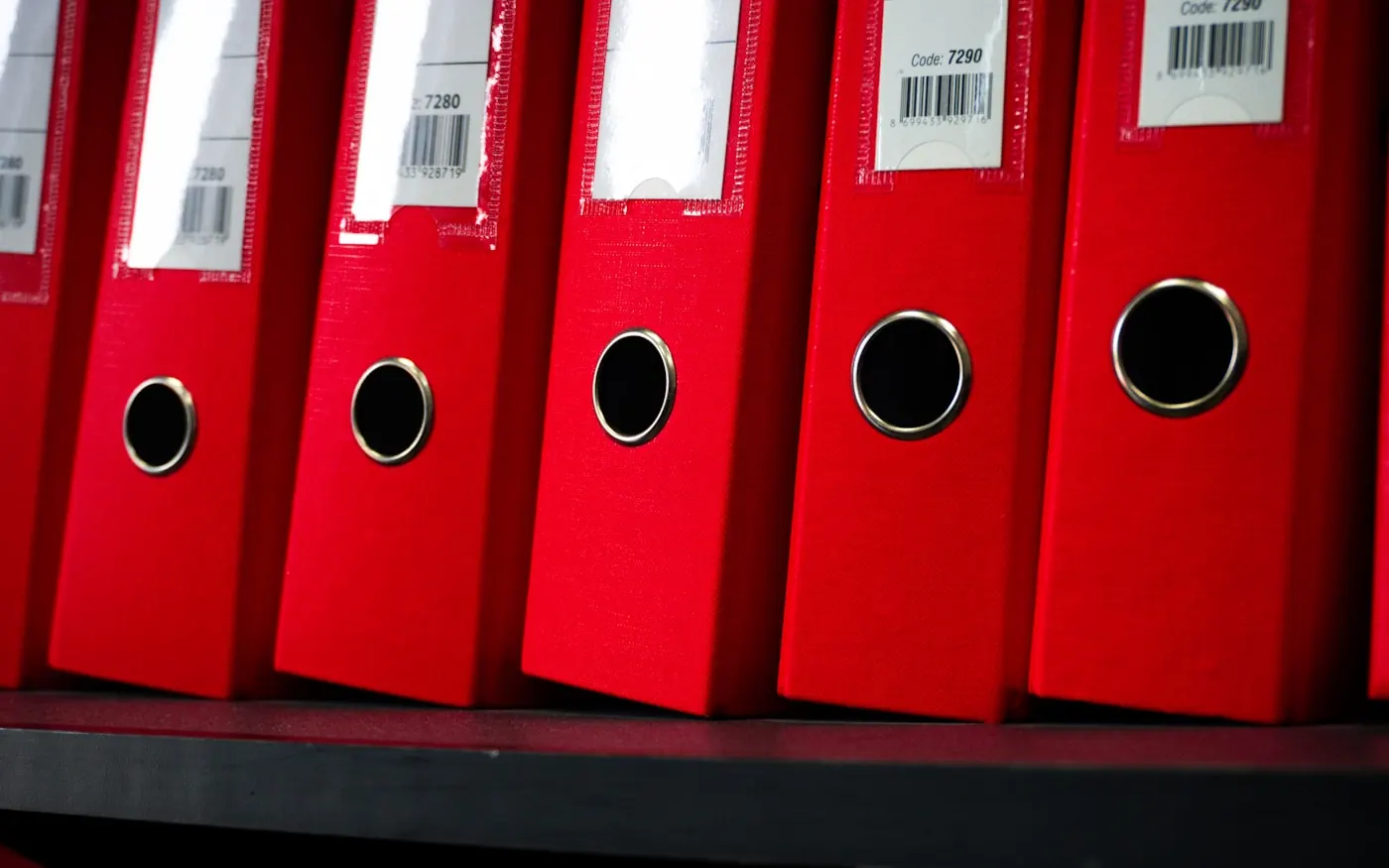 Carpetas de expedientes archivadas en una estantería de oficina